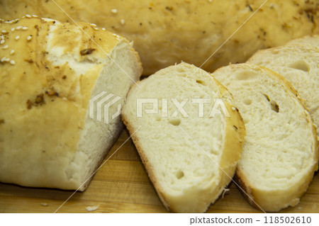 Wheat bread baked from flour at home. Sliced bread on wooden board against background. Food with NO GMO. Homemade bread with spice on it. Wheat bread baked from flour at home. Sliced bread on wooden board against background. Food with NO GMO. Homemade bread with spice on it. 118502610