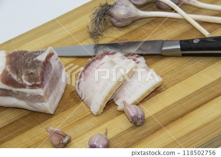 Ukrainian products raw lard with peppercorn and garlic, knife, slices of salo being on cutting board. Ukrainian traditional food concept. Ukrainian products raw lard with peppercorn and garlic, knife, slices of salo being on cutting board. Ukrainian traditional food concept. 118502756
