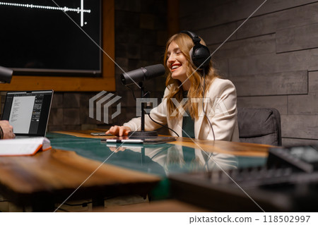 A woman is equipped in a studio to record a podcast professionally with modern audio technology A woman is equipped in a studio to record a podcast professionally with modern audio technology 118502997