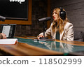 Podcaster recording with headphones and microphone in studio, chatting and broadcasting 118502999