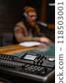 A podcaster is in a studio with recording equipment and microphones, ready to create content 118503001
