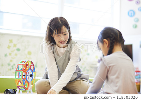 A female nursery teacher plays with children using toys at a nursery school A female nursery teacher plays with children using toys at a nursery school 118503020