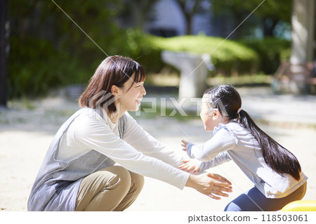A smiling nursery school teacher hugging a child A smiling nursery school teacher hugging a child 118503061