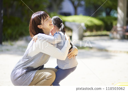 A smiling nursery school teacher hugging a child A smiling nursery school teacher hugging a child 118503062