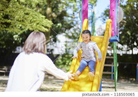 A female nursery school teacher welcomes the children playing on the slide. A female nursery school teacher welcomes the children playing on the slide. 118503065
