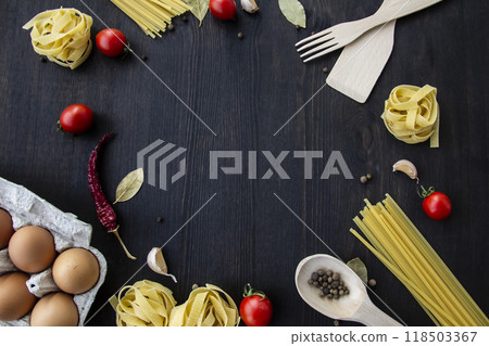 Cooking food background with free space for text. Composition with spaghetti, tomato, eggs, garlic, bay leaf over the wood background. Ingredients for cooking with copy space. Top view for the design 118503367