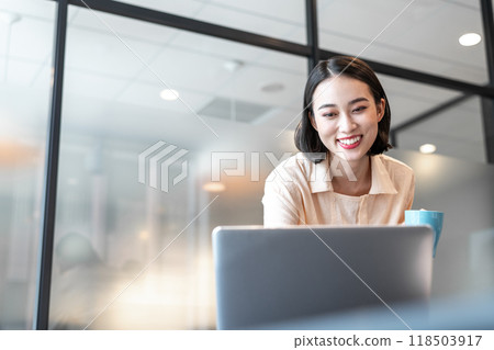 A woman smiling while looking at a computer screen during a break 118503917