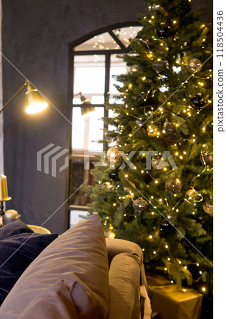 Christmas interior with a beautiful Christmas tree, sofa, light bulbs and dark background. Christmas interior with a beautiful Christmas tree, sofa, light bulbs and dark background. 118504436