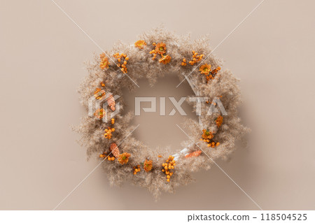 Wreath for Thanksgiving Day with orange flowers and dry natural materials on beige background. Top view. Greeting card with copy space. 118504525