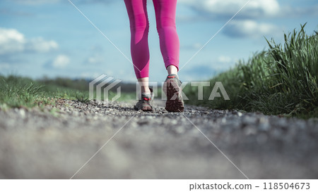 female legs in pink leggings taking a step on gravel country road 118504673