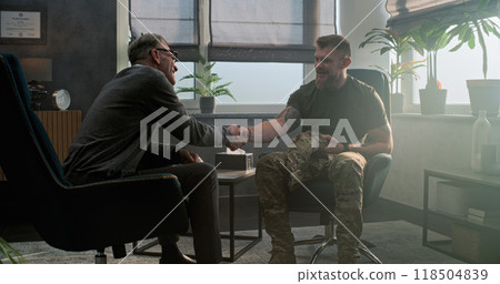 Caucasian military man discusses progress with psychiatrist after treatment Caucasian military man discusses progress with psychiatrist after treatment 118504839