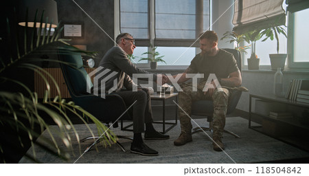 Senior psychologist says goodbye to soldier and looks at camera while sitting in chair 118504842