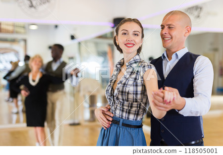 Man and woman performing ballroom dance in dancing room 118505001