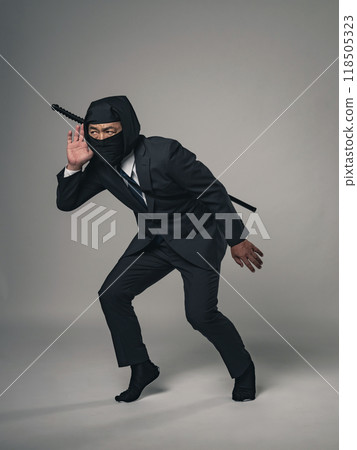 Full-body photo of a ninja wearing a business suit listening intently 118505323
