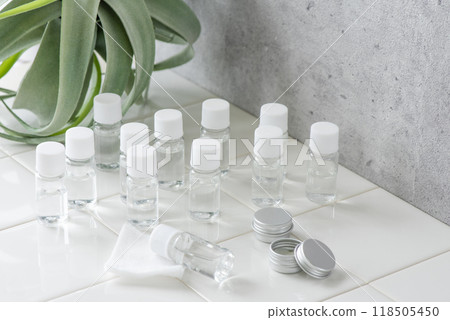 白色瓷磚上放置的迷你瓶化妝品樣本和室內植物 118505450