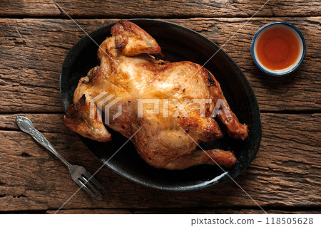 Golden Roasted Chicken in Rustic Black Plate on old wooden table Golden Roasted Chicken in Rustic Black Plate on old wooden table 118505628