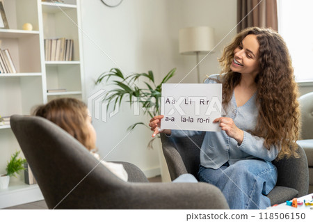 Cute smiling young speech therapist with table with written syllables in hands 118506150