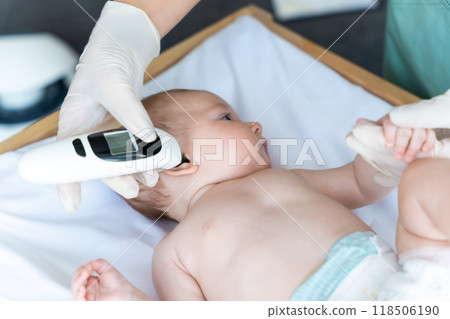 Female pediatrician with digital infrared thermometer measuring baby girl patient's ear temperature Female pediatrician with digital infrared thermometer measuring baby girl patient's ear temperature 118506190