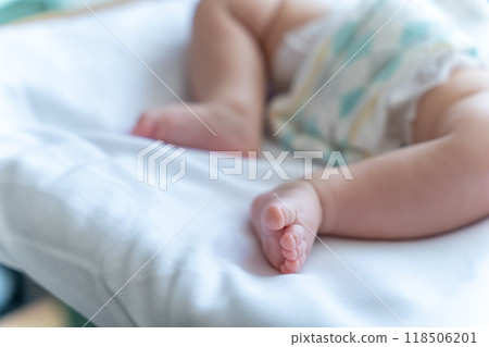 Unrecognizable infant child wearing diaper baby's feet on bed, copy space Unrecognizable infant child wearing diaper baby's feet on bed, copy space 118506201