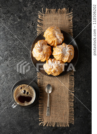 Cream cakes and black coffee on a black table. Cream cakes and black coffee on a black table. 118506202