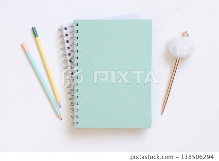 Blank spiral notebook on a white table near fur pen and pensils, school mockup 118506294