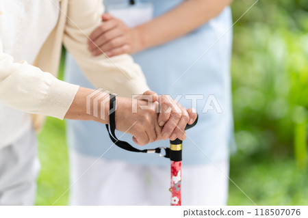 拿著拐杖和護理人員的手的高級婦女 118507076