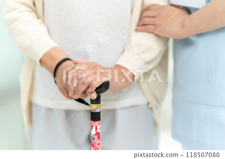 Senior woman with a walking stick and the hands of a caregiver 118507080