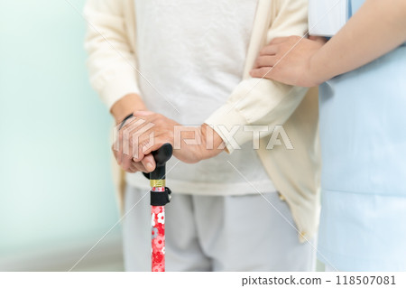 拿著拐杖和護理人員的手的高級婦女 118507081