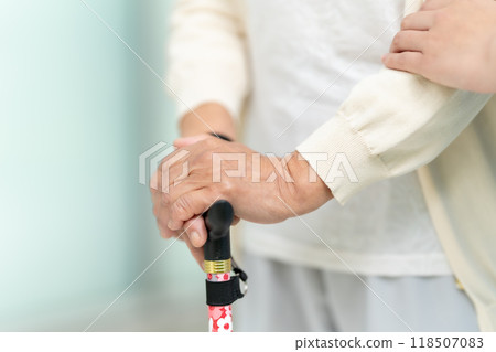 Senior woman with a walking stick and the hands of a caregiver 118507083