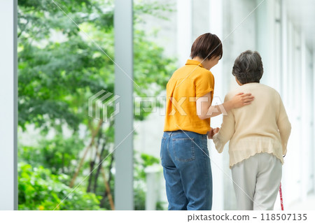 A woman walking while supporting an elderly woman, back view 118507135
