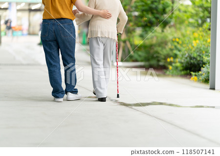 A woman walking while supporting an elderly woman A woman walking while supporting an elderly woman 118507141