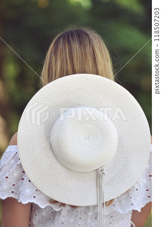 Closeup back view of woman in white hat looking out towards . 118507203