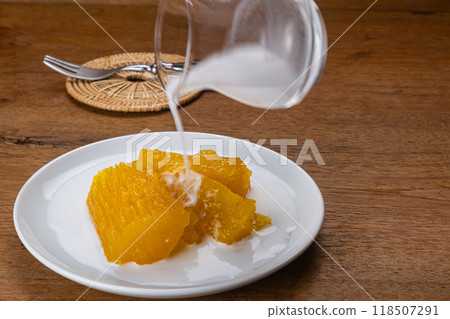 High angle view pouring coconut milk on cassava or tapioca in syrup. High angle view pouring coconut milk on cassava or tapioca in syrup. 118507291