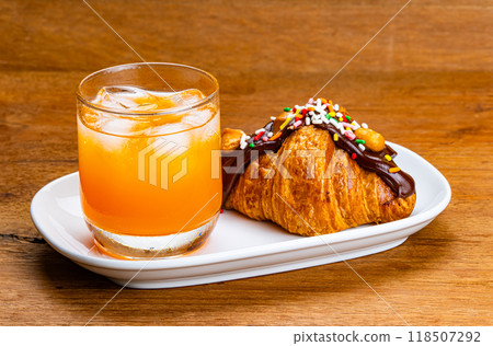 Cold orange juice and croissant in white ceramic tray. Cold orange juice and croissant in white ceramic tray. 118507292