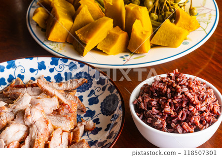 Steamed riceberry in white ceramic bowl with sliced roasted pork and pieces of pumpkin. Steamed riceberry in white ceramic bowl with sliced roasted pork and pieces of pumpkin. 118507301