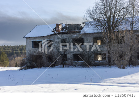 Abandoned building in a winter landscape, bathed in sunlight on snowy ground. Roof caved in, windows broken, telling a story of ruin and decay. Lonely and spooky, a reminder of the past. 118507413