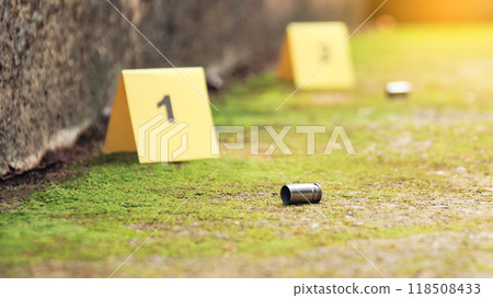 Spent bullet casing lying on the ground with blur number 1 sign. Concepts of shooting sports and security highlighting the dual nature of firearms in both competitive sport and protective measures. 118508433