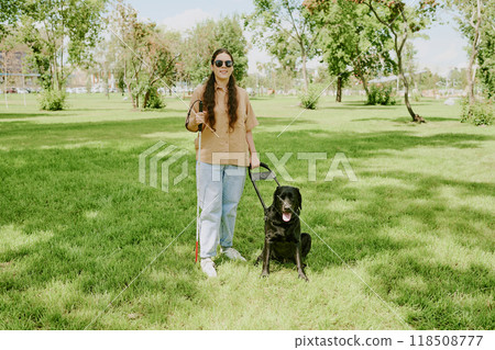 Young Caucasian woman with disability enjoying sunny day while spending time with her guide dog in park 118508777