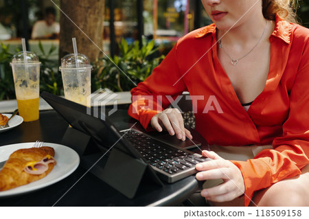 Woman Working on Laptop at Outdoor Cafe Table Woman Working on Laptop at Outdoor Cafe Table 118509158