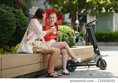 Women Chatting While Sitting on Urban Bench Outdoors 118509202