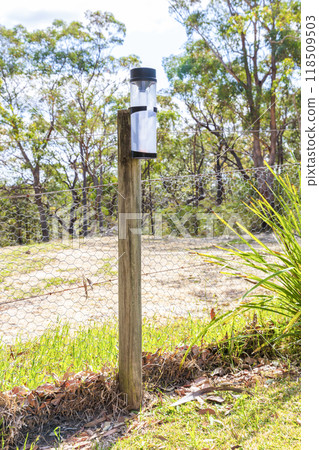 A rain gauge near a fence on a rural property 118509503