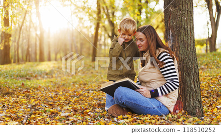 Mother and child reading book in autumn park Mother and child reading book in autumn park 118510252