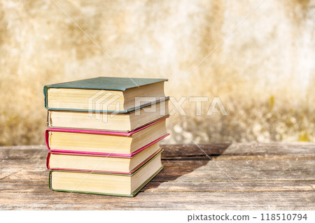 Old books against the background of a shabby wall plaster Old books against the background of a shabby wall plaster 118510794