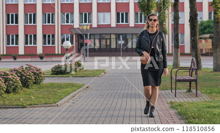 Businesswoman is walking in a city park, enjoying the sunshine and fresh air during her lunch break Businesswoman is walking in a city park, enjoying the sunshine and fresh air during her lunch break 118510856