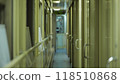 Narrow corridor with doors on the right and a handrail on the left winds through the train cars 118510868