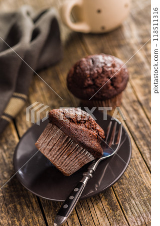 Sweet chocolate muffin cakes on plate on wooden table. 118511316