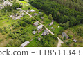 Aerial view of a small village with traditional wooden houses, surrounded by lush green forest and a winding river 118511343