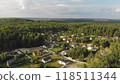 Aerial view of a residential area with new detached houses with green lawns and fences surrounded by forest 118511344