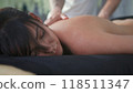 Masseuse giving back massage to relaxed woman in spa 118511347