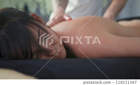Masseuse giving back massage to relaxed woman in spa Masseuse giving back massage to relaxed woman in spa 118511347